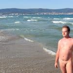 The boy od sunbathing naked on the beach.
