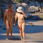 Couple of nudists walks along the beach