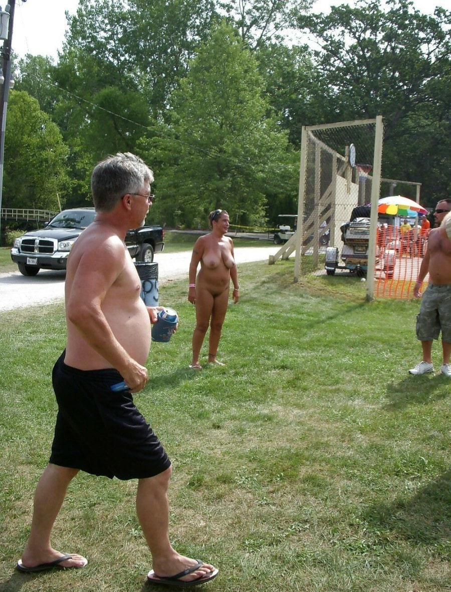 busty milf - Public Park Nudity: MILF Flashes in the Grass A MILF flashes in a public park setting, fully nude with small perky tits and a clean-shaven pussy, standing casually with two men in a grassy area. - Boobs Flash Pics