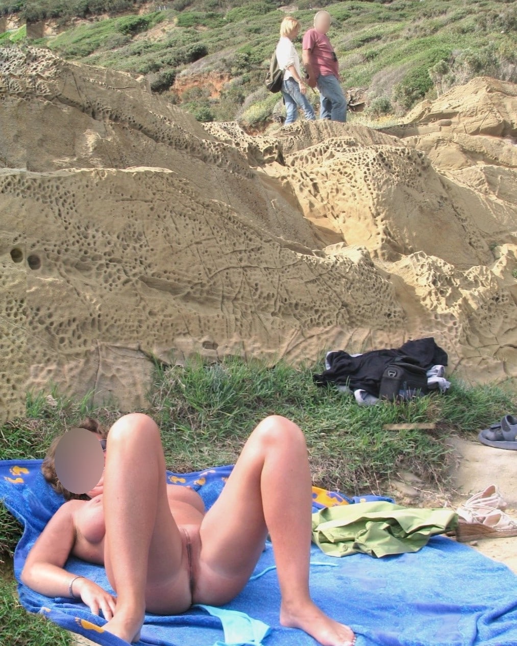 Ass Flash Pics: Who’s Watching Her Spread Eagled on the Beach? A nude woman lies spread eagled on a beach towel, legs wide open, in a rocky coastal area. Voyeuristic figures blur in the background, adding to the public n...