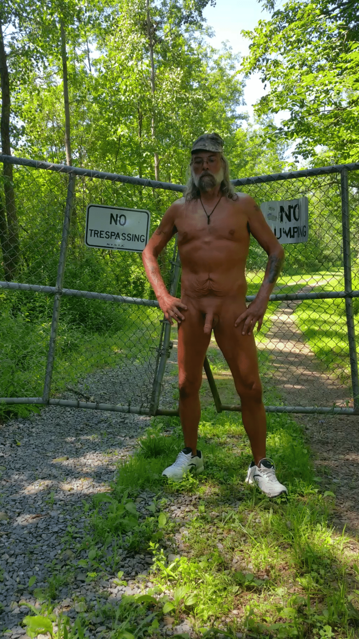 flashing outdoor - Public Nudity: Gate Nude with a View A man stands nude in front of a chain-link fence with a 'NO TRESPASSING' sign, showcasing public nudity and defiance. - Dick Flash Pics