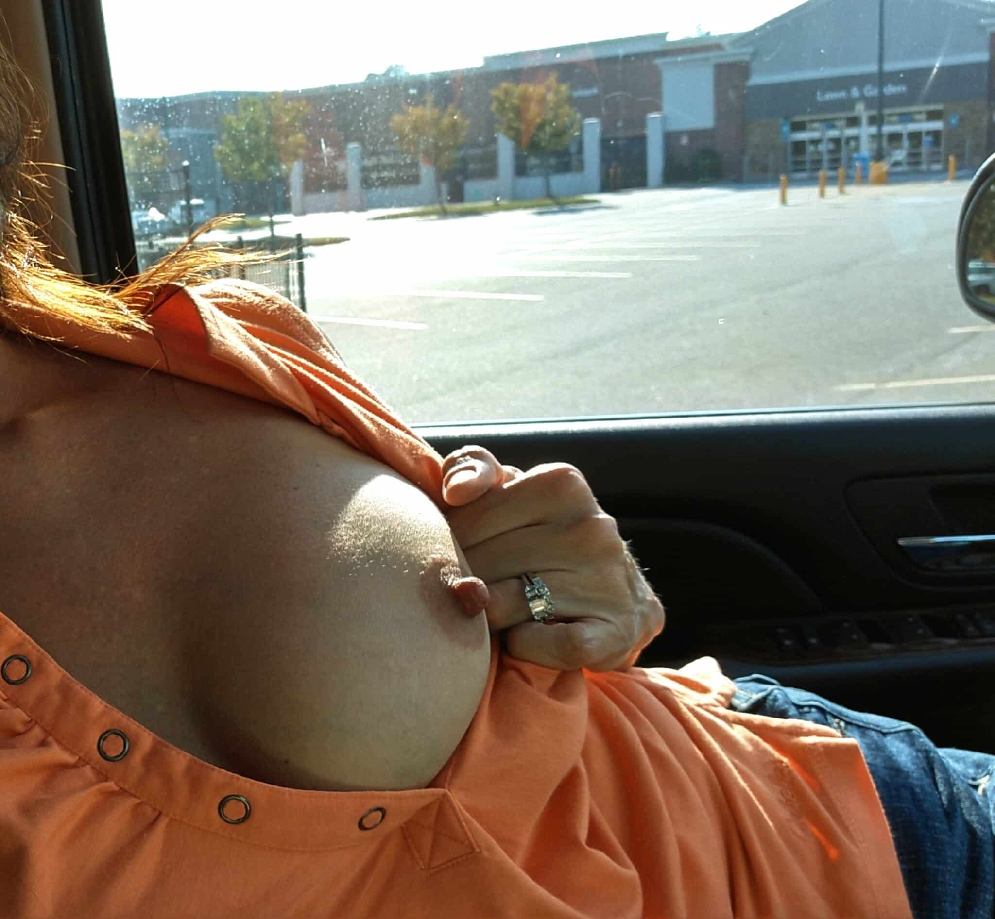 Boobs Flash Pics: Walmart Parking Lot Flashing: A Bold Display of Public Nudity A woman flashes in a Walmart parking lot, exposing her large breasts while pinching her nipple, a bold display of public nudity.